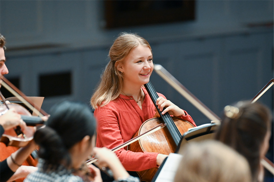 Female student enjoying herself and playing the cello in an orchestra